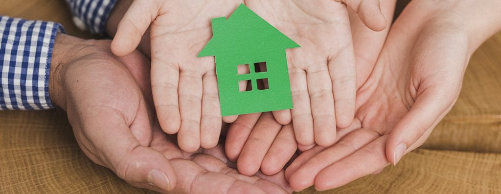 Mani di iomo donna e bambini tengono casa di carta verde